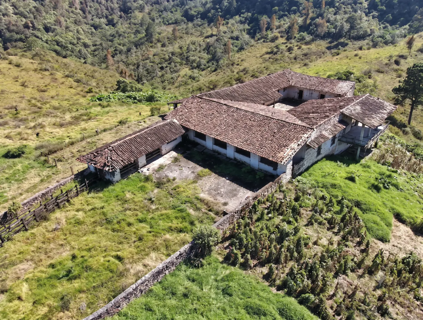 Vista aérea de la casona de piedra del rancho, con cubierta de teja, sobre la ladera.