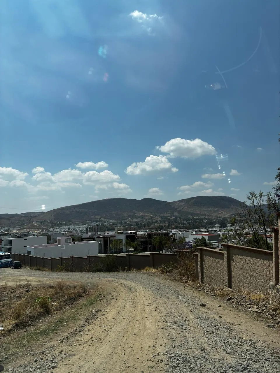 Camino de terracería que bordea la reserva, con el valle y los cerros al fondo.